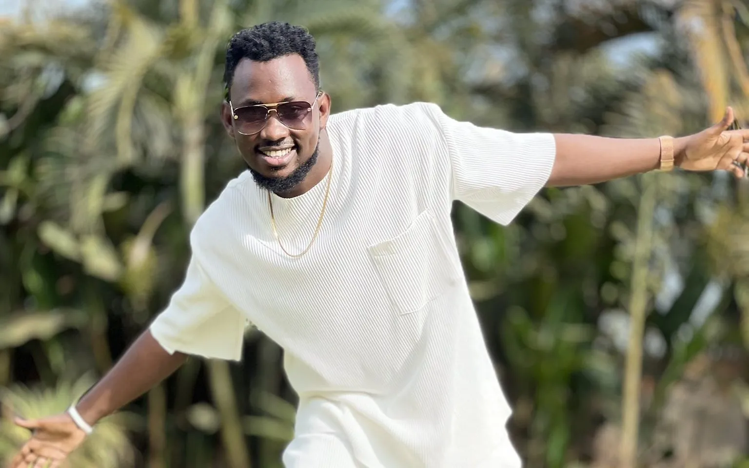 Levixone smiling outdoors in an all-white outfit and sunglasses, arms wide open