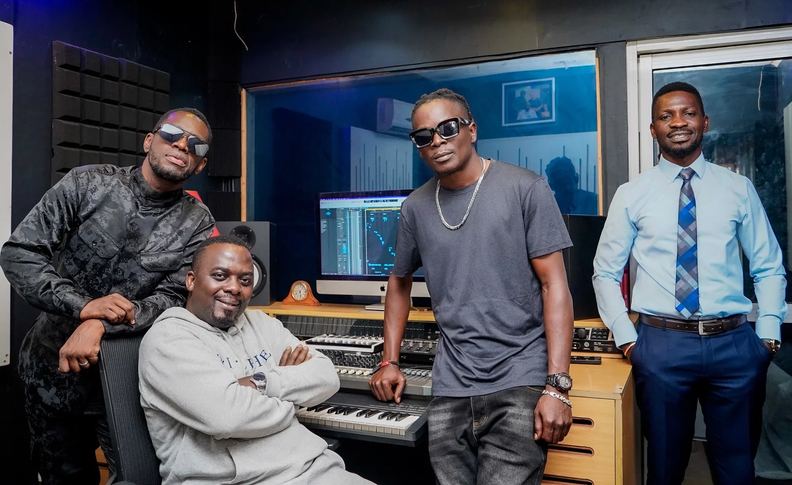 King Saha, Bobi Wine, and Nubian Li recording music together at Audio One studio, seated around a mixing console with headphones and microphones.